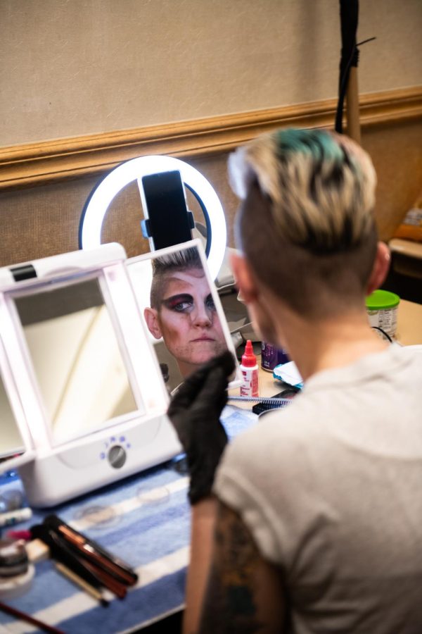 Drag King MaveRick applies their makeup backstage before the show