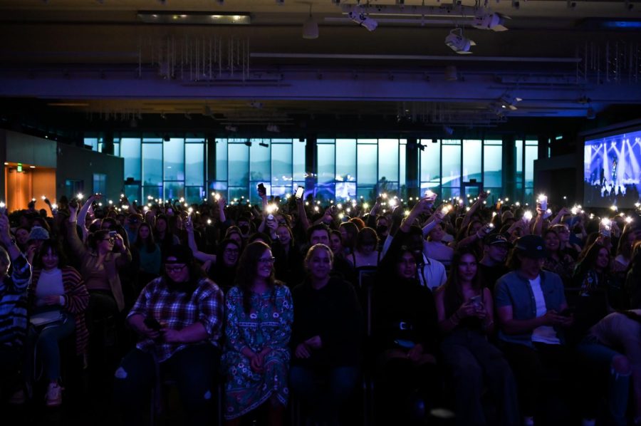 Audience members cheer and shine phone flashlights during a drag artist’s performance