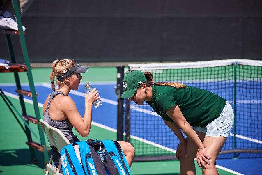 Colorado State Junior, Sarka Richterova, plays against University of Wyoming. Coah Mai-Ly Tran advises her with playing strategy for the next match while Richterova hydrates.