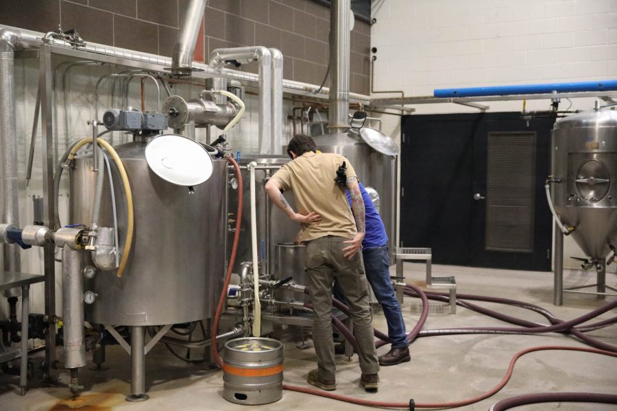 Two people peer into a vat in Odell Brewing Companys processing room April 6. This room is located behind the bar that is open to the public.