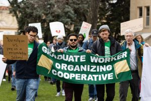 Some people hold a sign that says Graduate Worker Organizing Cooperative.