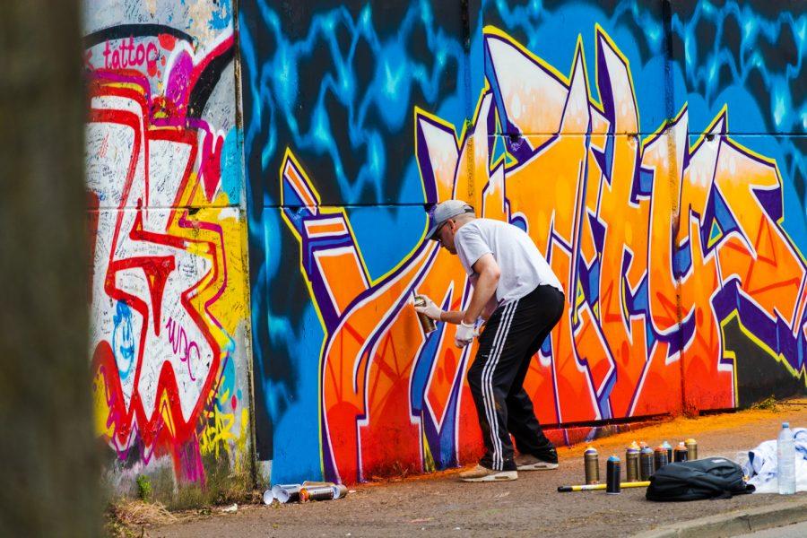 A man spray paints a section of the Belfast Peace Wall