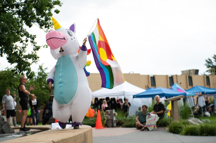 A person inside of an inflatable unicorn costume waves a Colorado Pride flag during a performance at the 2022 NoCo Pride Festival