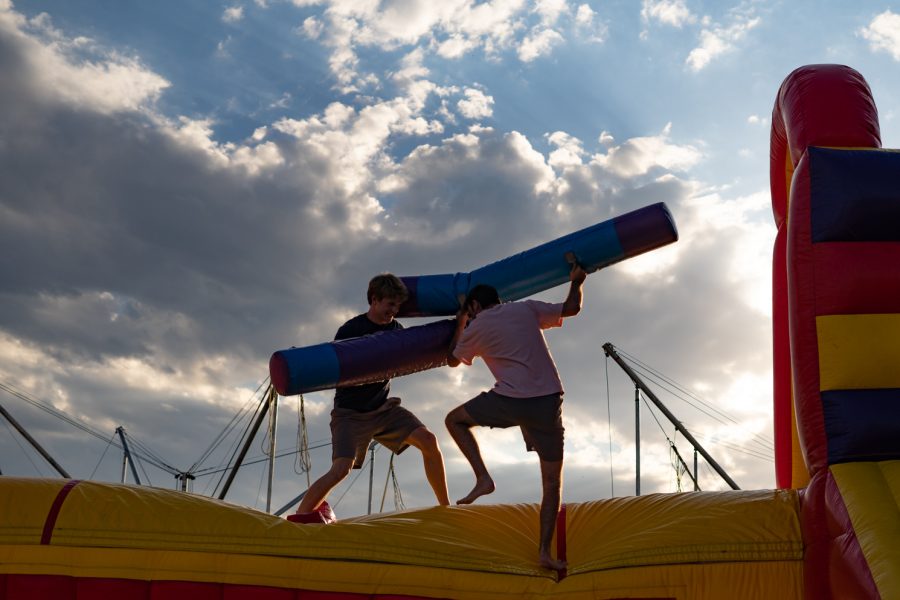 Two students hit each other with inflatable tubes on an inflatable obstacle course at the Carnival.