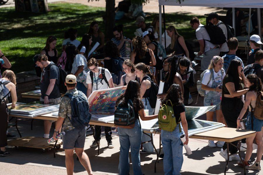 Students look through posters at the Poster Invasion tent on the Colorado State University Plaza
