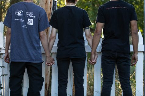Three people stand in a line holding hands