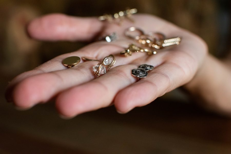 A variety of earrings lay spread out on a persons hand on
