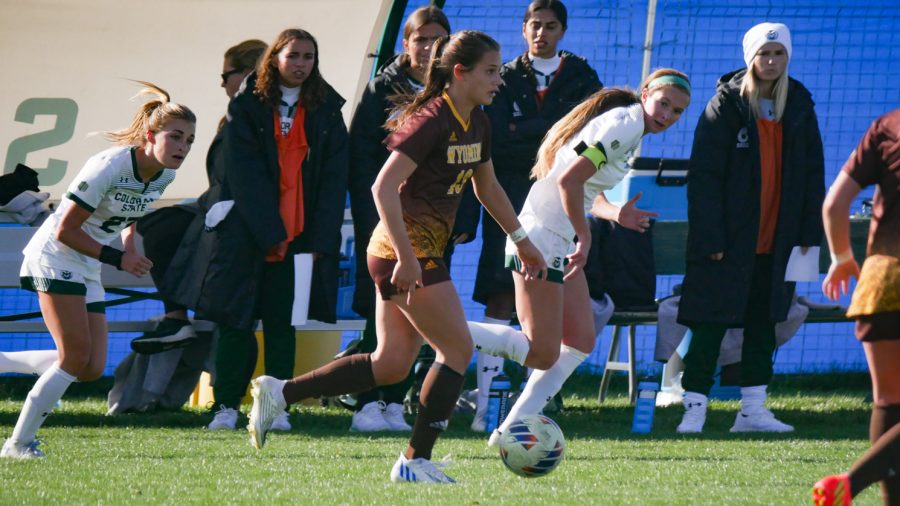 Wyoming defender Sydney Miller (13) looks to pass the ball upfield as Colorado State forward Caroline Lucas pursues Oct. 27.