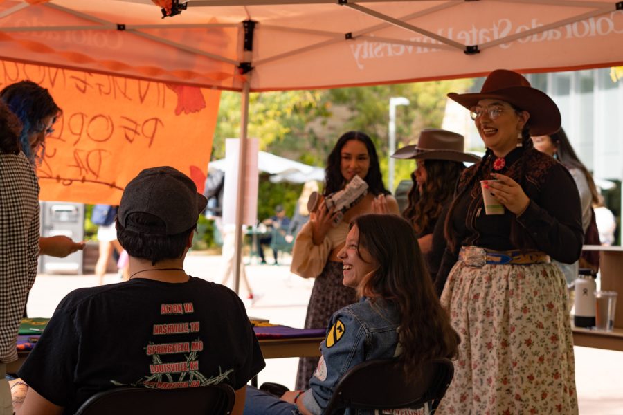 Members of the Native American Cultural Center talk at their booth set up for Indigenous Peoples' Day on the Plaza