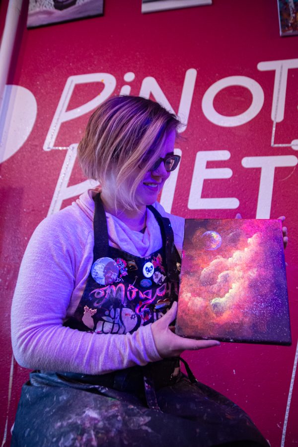 Morgan Lindquist, studio manager and artist, paints a picture of the galaxy with ultraviolet acrylic paint