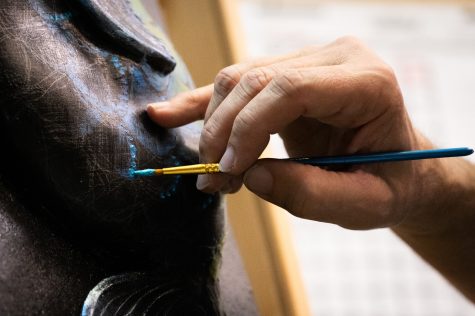 Adam Schultz paints small details and stippling marks onto the scales of the fish he creates as a piece for the mask project put on annually by the Museum of Art Fort Collins Nov. 23, 2022.