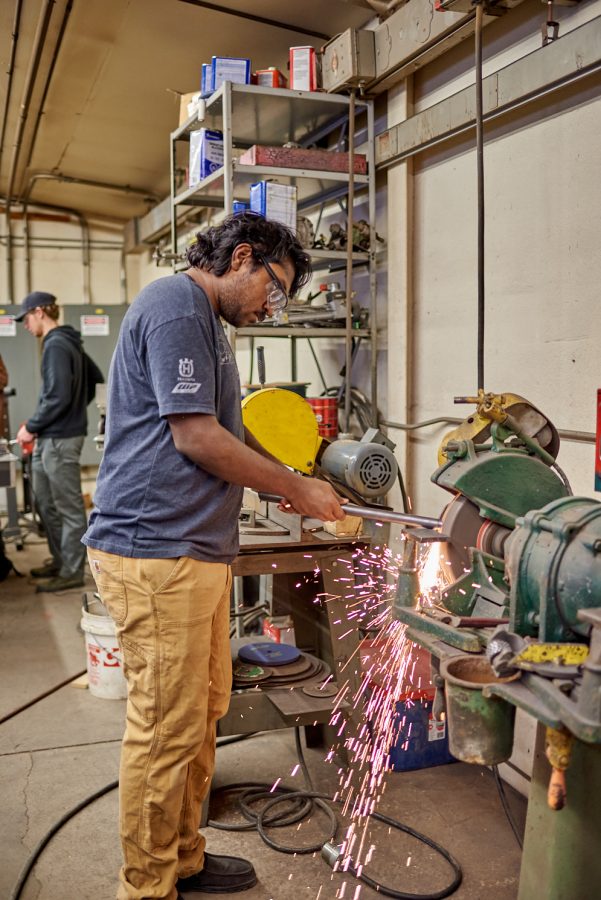 Sudhish Raghupatruni, senior biomedical and mechanical engineering student, grinds a metal tube on a bench grinder at the Engineering Research Center Jan. 28. The bench grinder spins a disk at high speed to remove material from the pipe.