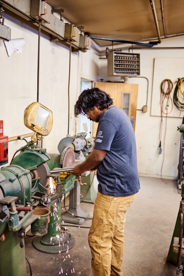 Sudhish Raghupatruni, senior biomedical and mechanical engineering student, grinds a metal tube on a bench grinder at the Engineering Research Center Jan. 28. The bench grinder spins a disk at high speed to remove material from the pipe.