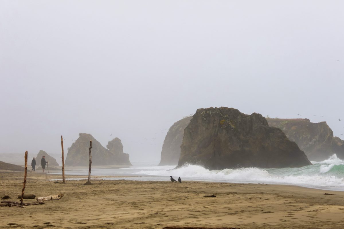 Two people walk along a hidden beach on the coast of Northern California as fog moves inland July 13.
