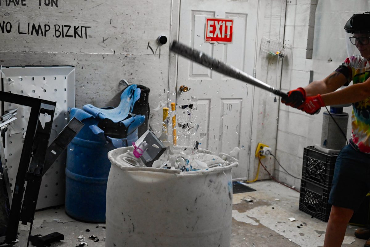 Shatter Rage Room owner Caitlin Nelson destroys glass cups and plates.