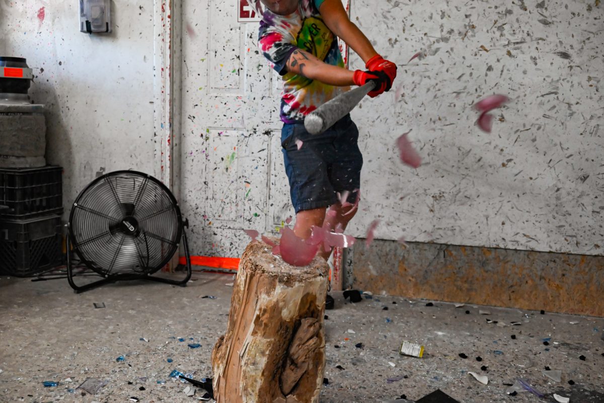 Shatter Rage Room owner Caitlin Nelson smashes a red vase.