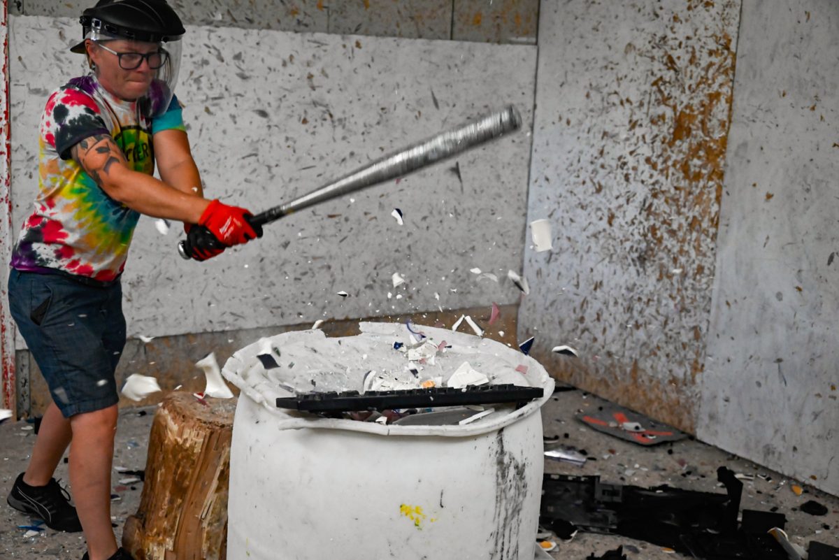 Shatter Rage Room owner Caitlin Nelson destroys a keyboard and some glassware.
