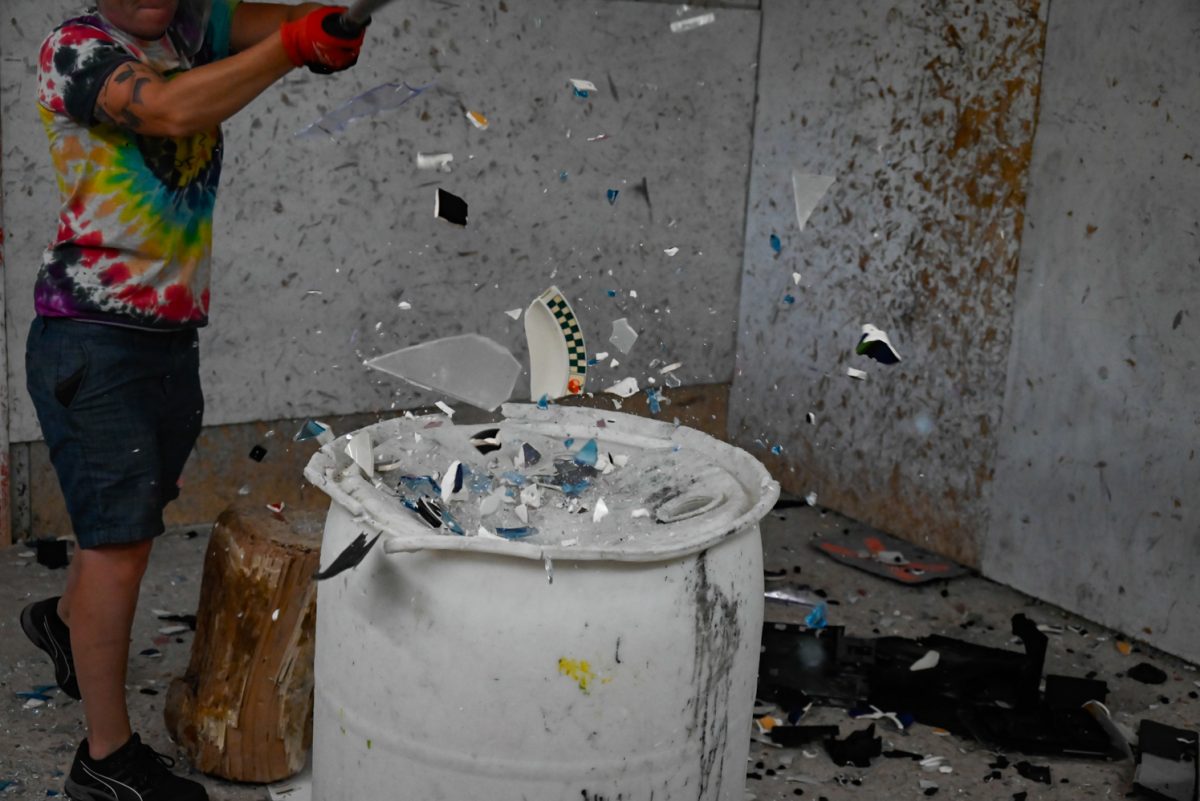 Shatter Rage Room owner Caitlin Nelson destroys plates and a blue glass.
