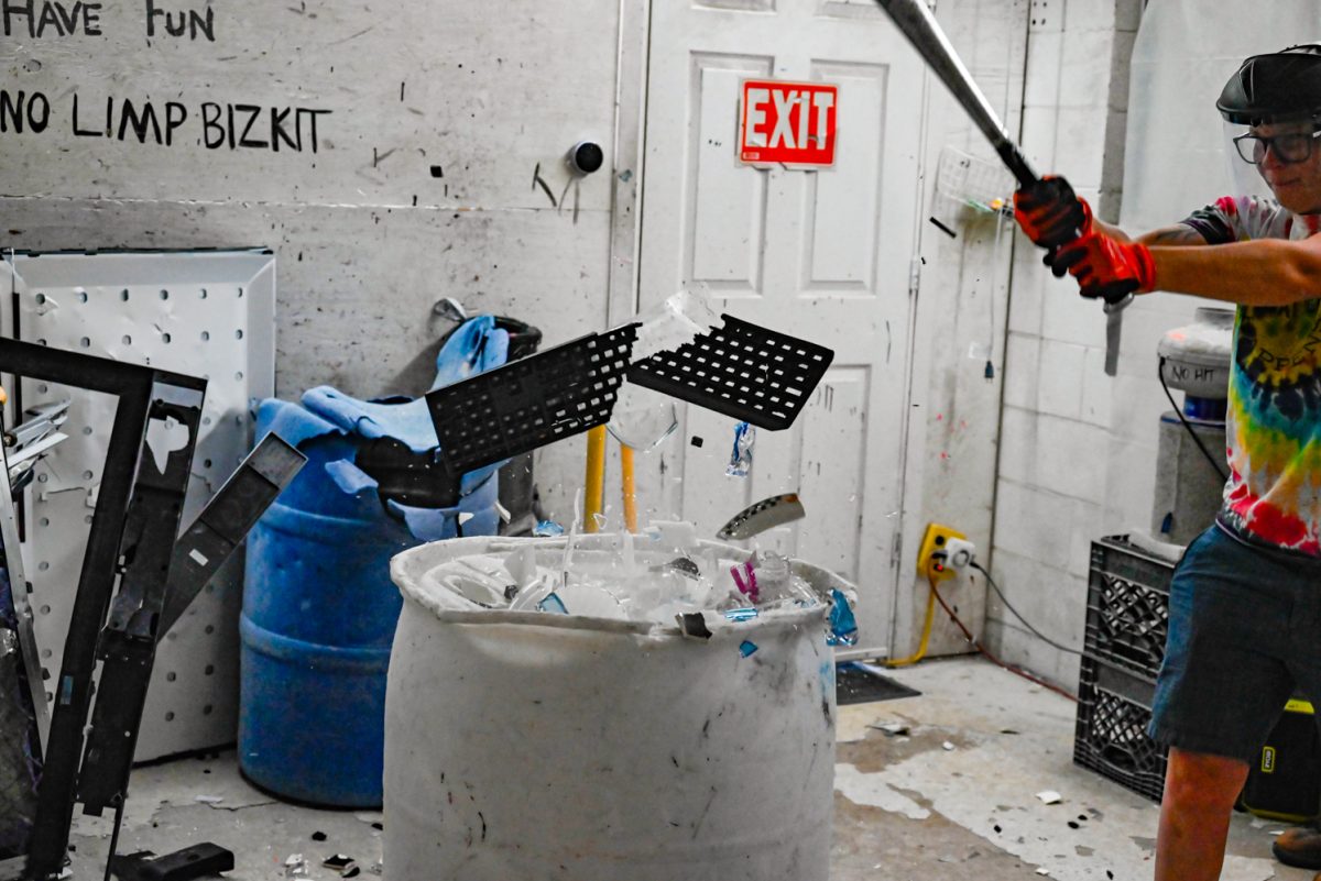 Shatter Rage Room owner Caitlin Nelson smashes a keyboard with a bat.