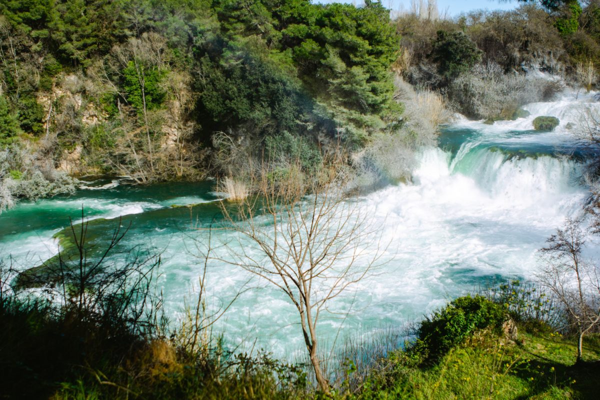 A large waterfall is behind a faint but visible rainbow.