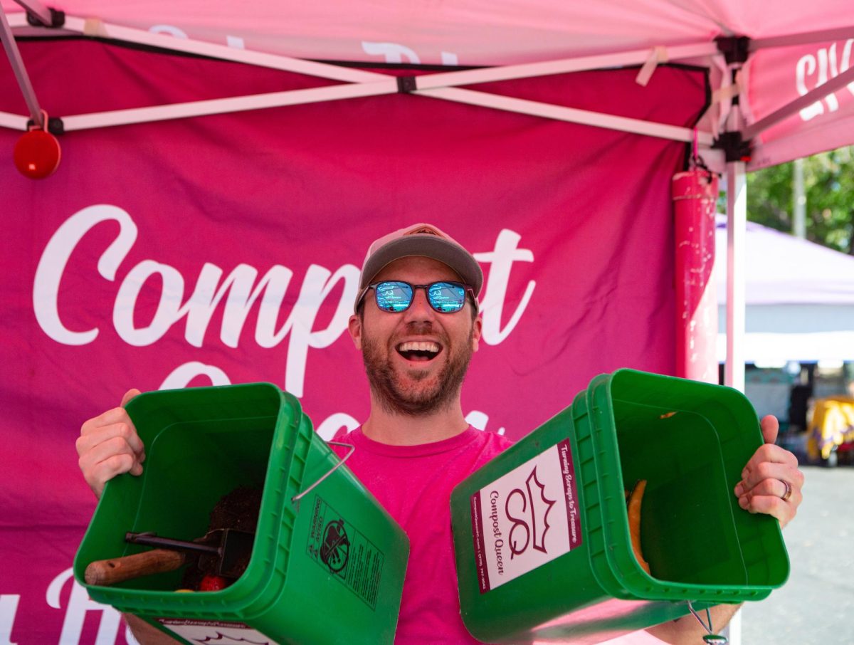 Max Poling holding up two compost bins at the Fort Collins Farmers Market located at the Ace Hardware parking lot; Max is part-owner of Compost Queen, a local composting company here in Fort Collins Sep. 17. "My wife and I started doing this five years ago now and we love it," said Poling, "We do composting for almost any type of residency and everything we compost goes from table to farm." Photo by River Kinnaird.