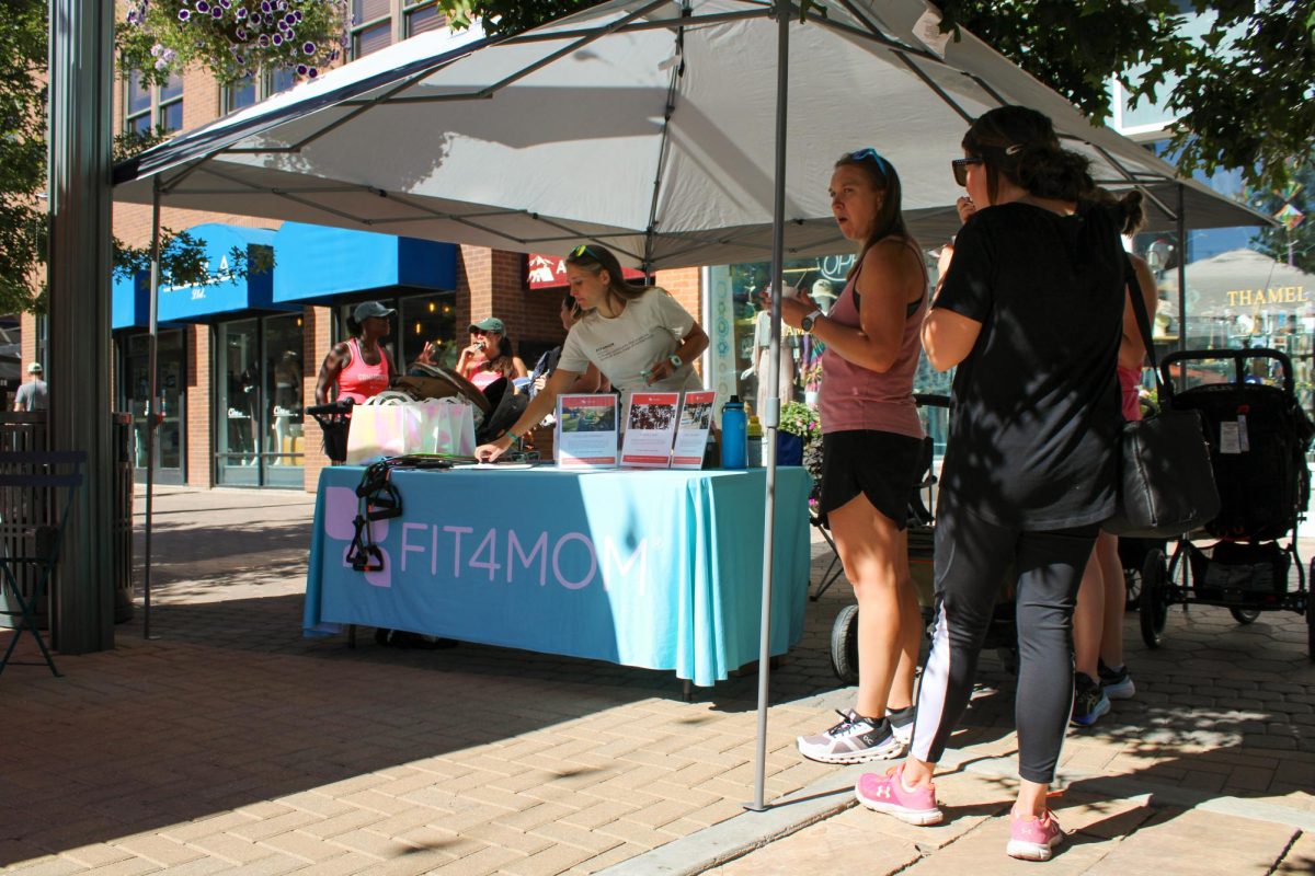 Nissa Lopez, one of two owners of FIT4MOM, places branded products on the companies table in Old Town Square Sept. 24. FIT4MOM is a fitness community for moms at all stages of motherhood. We have stroller-based fitness and mom only programs, Lopez said. We provide a supportive and inclusive enivornment for women to exercise after having kids. FIT4MOM has classes in Ft. Collins, Loveland, Windsor and Greeley.
