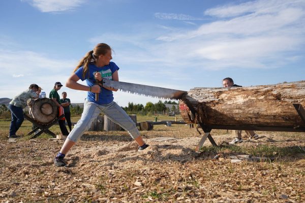 Annabelle Thomas and Eva Salm practice for the two buck event where they compete on how fast they can saw a cookie off of the log, while also keeping the width even Sept. 29.