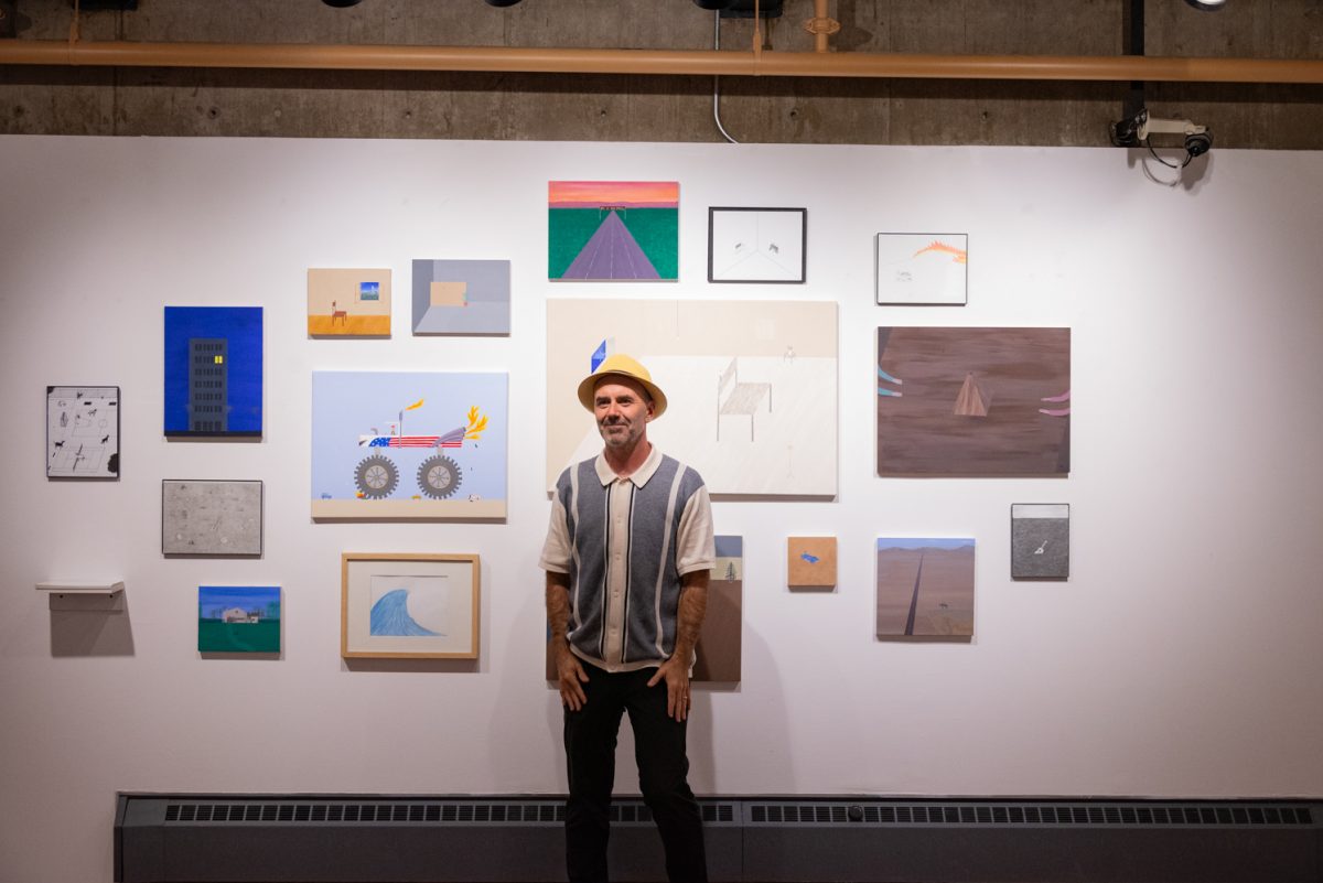 Aitor Lajarin-Encina, a painting instructor at Colorado State University, stands in front of a large collection of his paintings on display at the Directions Gallery.