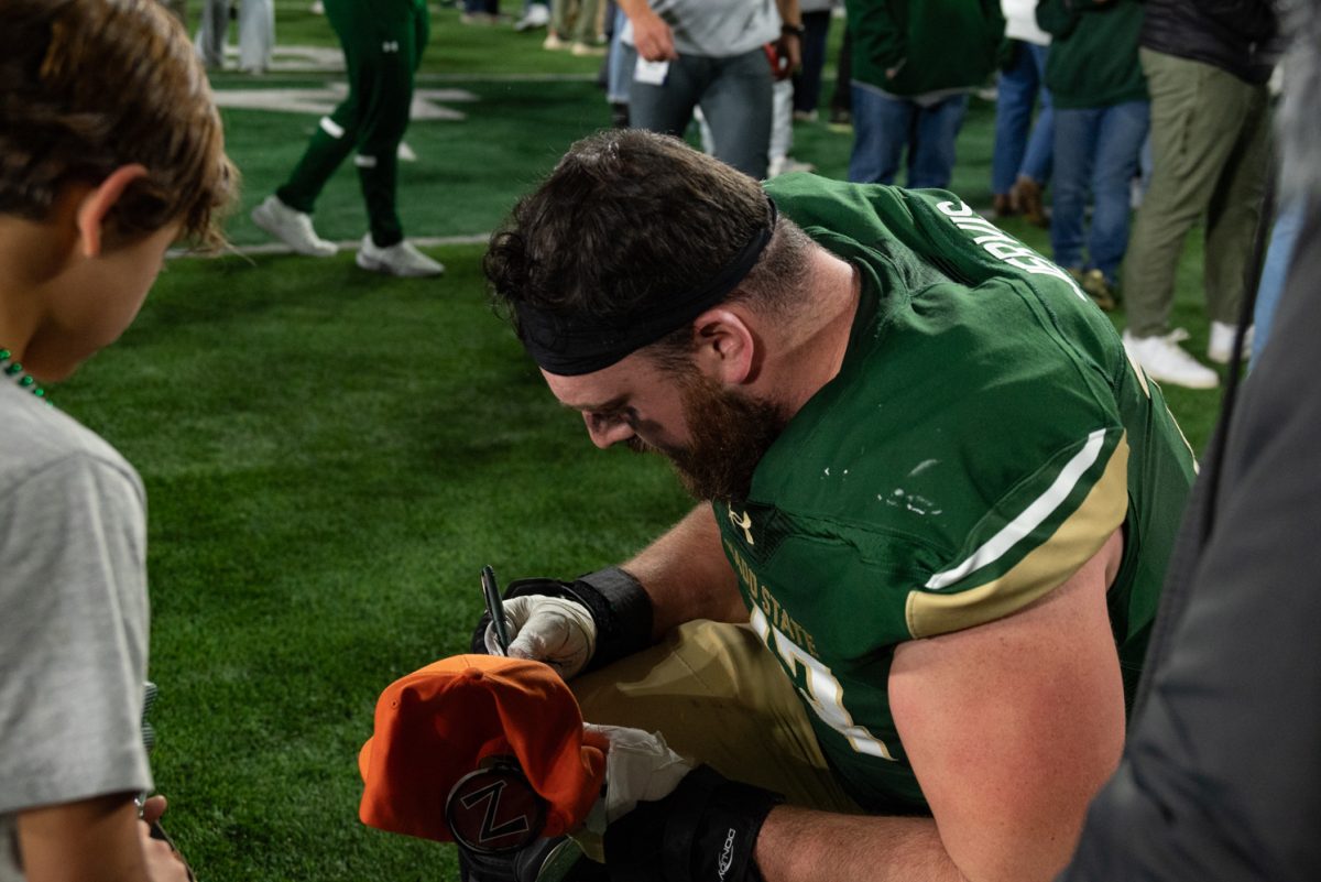 Graduate student Oliver Jervis (73) signs Jeremiah Sena's hat after the game.