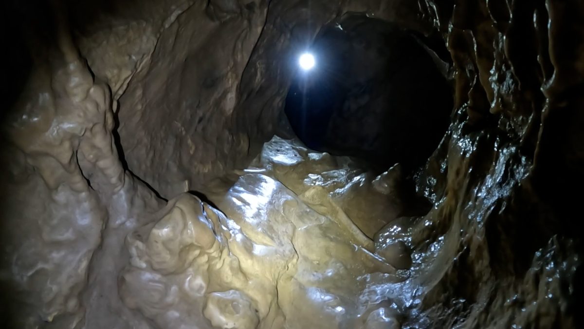 Eliot Krams stares down a tight passage preparing to crawl through in a cave Sept. 23.
