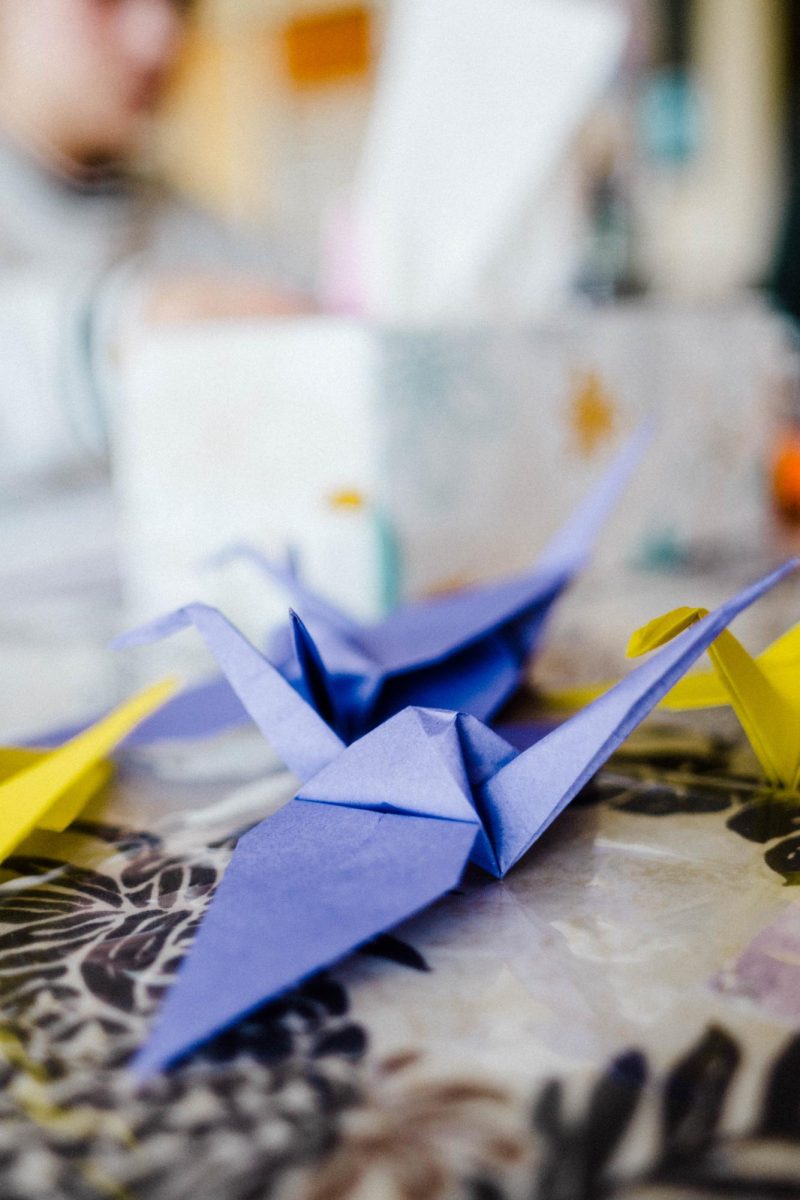 Folded+paper+cranes+sit+in+the+center+of+the+table+as+students+participate+in+the+Pride+Resource+Centers+crane+folding+event+for+Transgender+Day+of+Remembrance+Nov.+6.+Cranes+are+considered+holy+creatures+in+Japan+and+throughout+Asia%2C+and+the+gift+of+1%2C000+paper+cranes+is+said+to+bring+health+and+long+life.