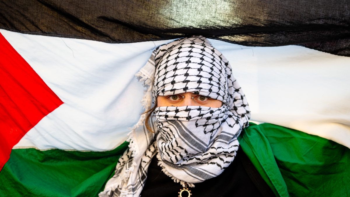 A protester in support of Palestine with their face covered by a shemagh holds a Palestinian flag behind their head during a protest outside the Colorado State Capitol building in Denver Colorado Nov.9.