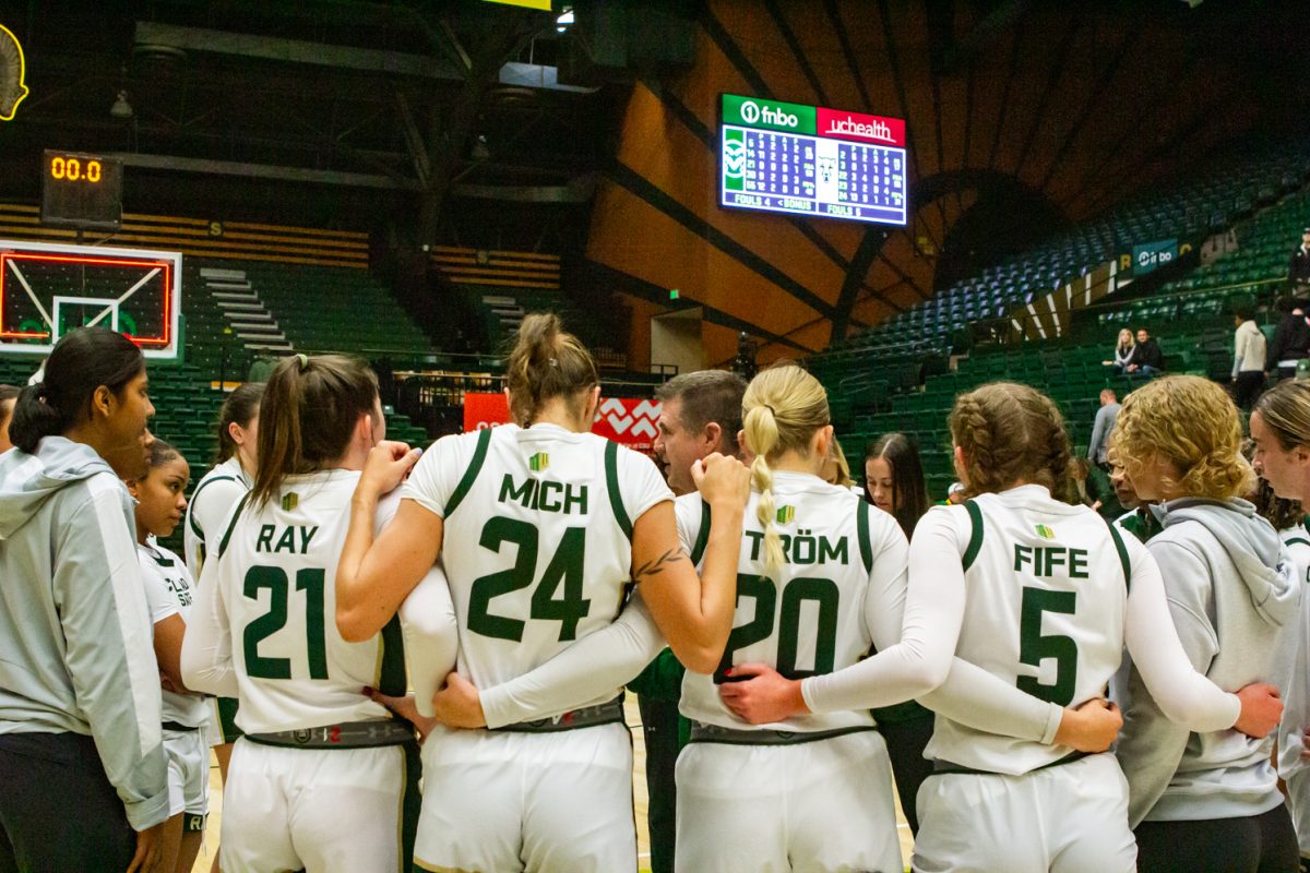 Women dressed in white athletic jerseys wrap their arms around one another as they celebrate their victory on the court.