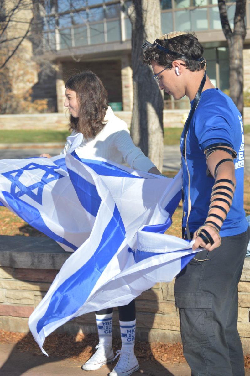 Two counterprotesters each hold a billowing Israel flag.