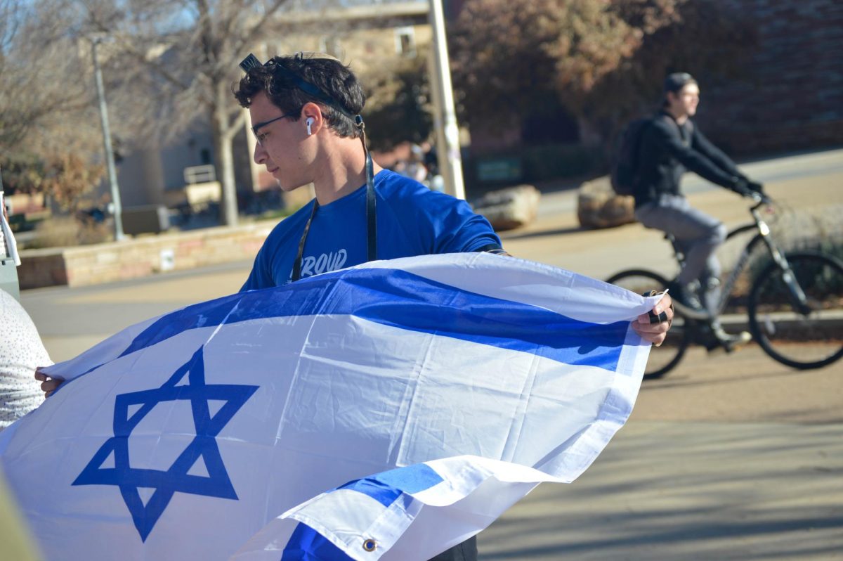 Bradley Berman waves an Israel flag in counter demonstration to the Free Palestine Protest on Nov. 10. Bradley and a few other Jewish students gathered to show support for Israel in the war against Hamas. 