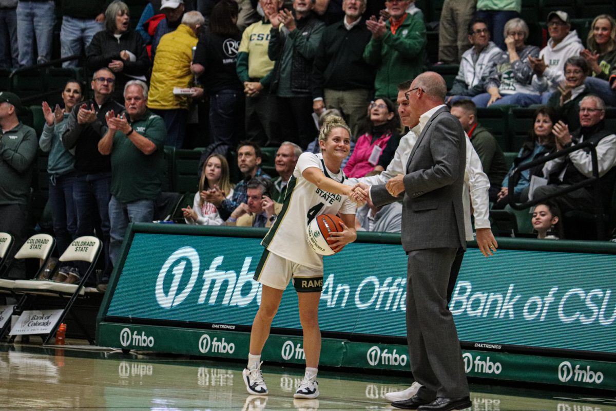 Colorado State University womens basketball guard McKenna Hofschild shakes CSU Director of Athletics Joe Parkers hand in Moby Arena Dec. 5, 2023. Hofschild was presented an honorary basketball for becoming the CSU all-time assist leader prior to the CSU game against High Point University.