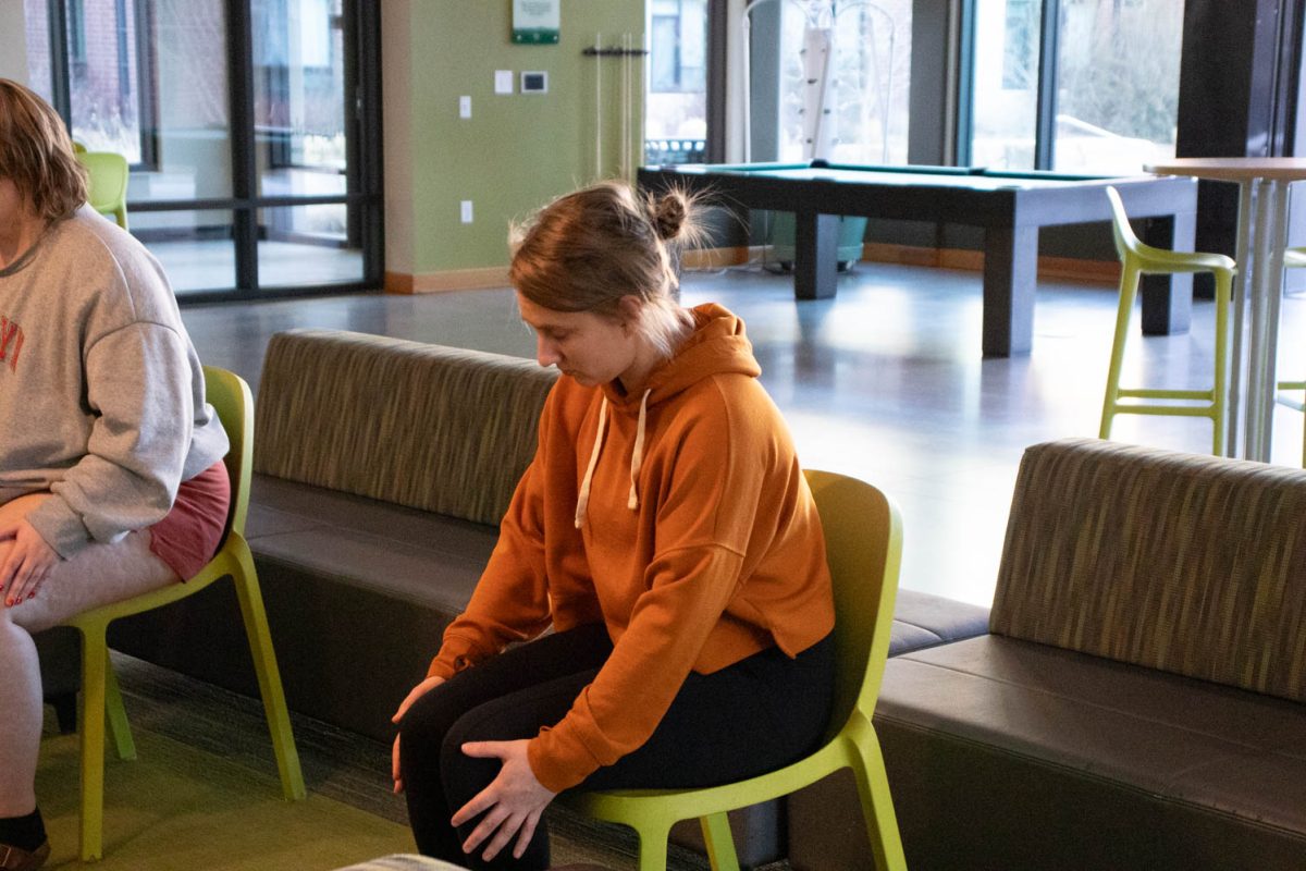 Megan Petersen stretches during seated wheelchair accessible yoga in the Aggie Village Lodgepole lobby on January 29, 2024.