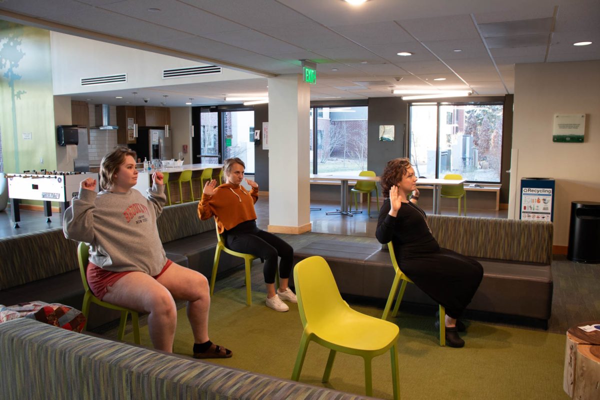 Torin Pruneski, Megan Petersen, and Eve Montoya stretch during seated wheelchair accessible yoga in the Aggie Village Lodgepole lobby on January 29, 2024.