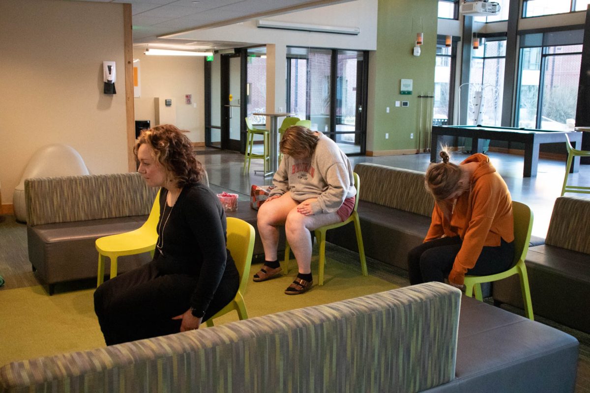Torin Pruneski, Megan Petersen, and Eve Montoya stretch during seated wheelchair accessible yoga in the Aggie Village Lodgepole lobby on January 29, 2024.