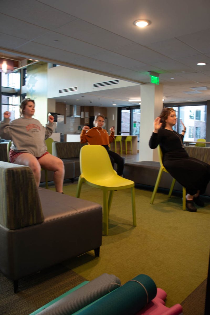 Torin Pruneski, Megan Petersen, and Eve Montoya stretch during seated wheelchair accessible yoga in the Aggie Village Lodgepole lobby on January 29, 2024.