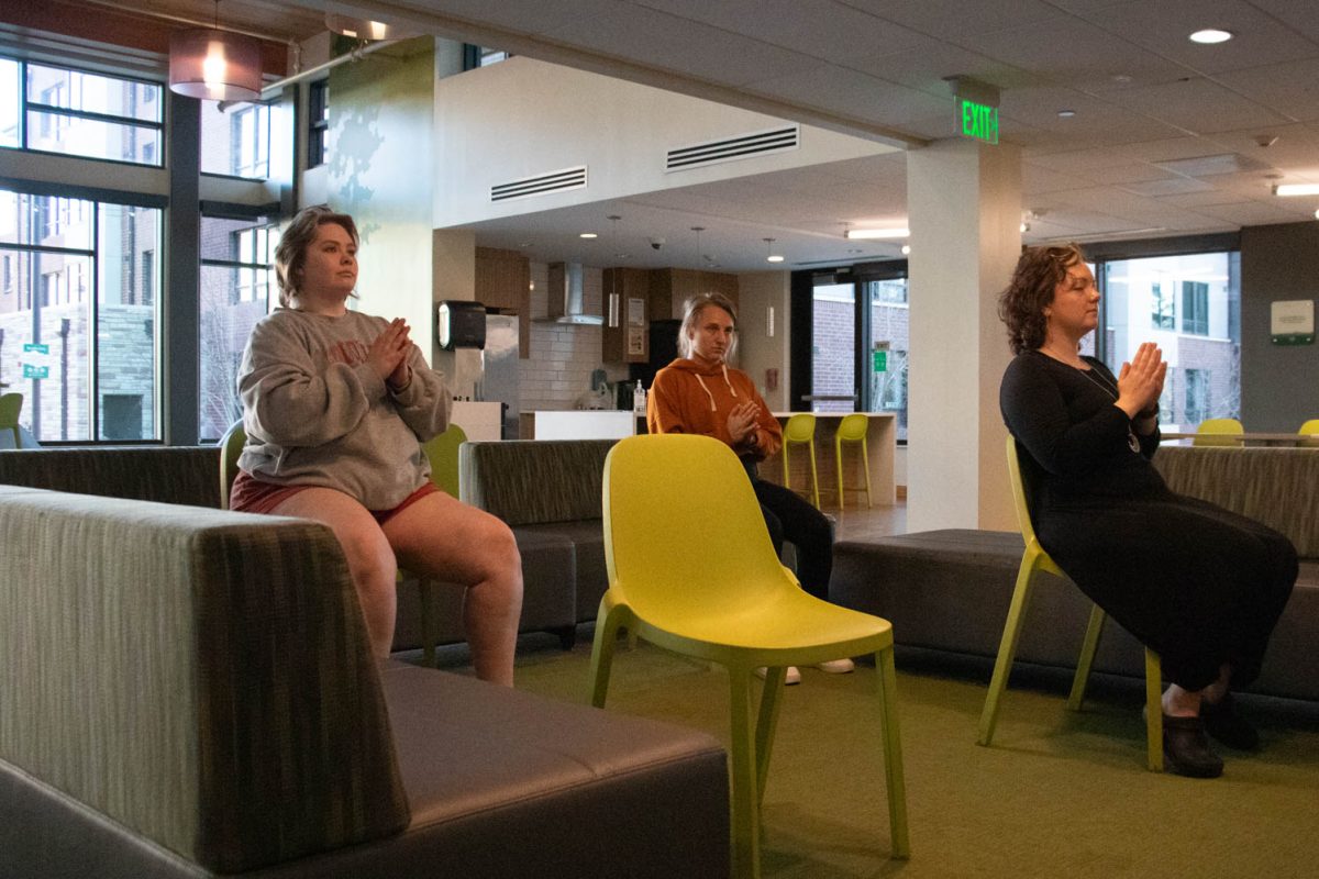 Torin Pruneski, Megan Petersen, and Eve Montoya stretch during seated wheelchair accessible yoga in the Aggie Village Lodgepole lobby on January 29, 2024.