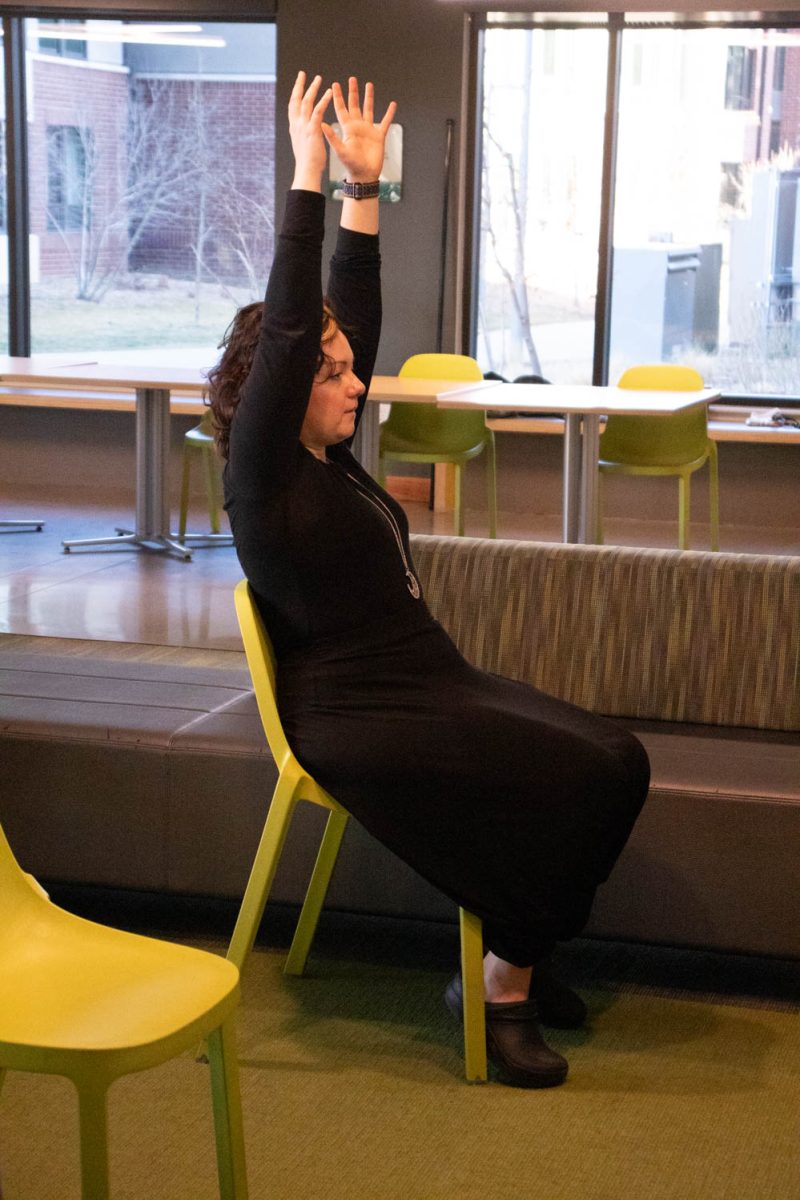 Eve Montoya stretches during seated wheelchair accessible yoga in the Aggie Village Lodgepole lobby on January 29, 2024.
