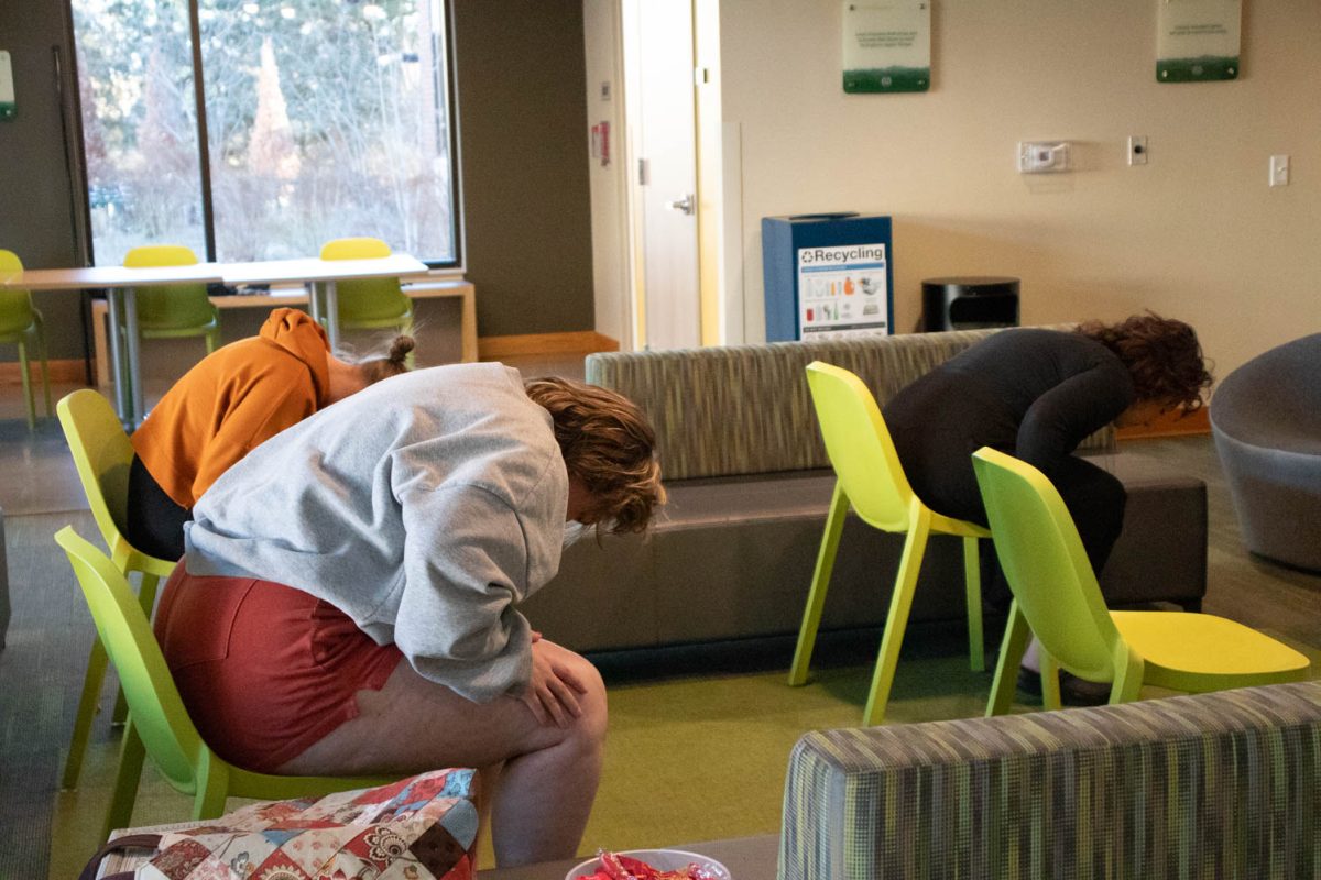 Torin Pruneski, Megan Petersen, and Eve Montoya stretch, following a YouTube video during seated wheelchair accessible yoga in the Aggie Village Lodgepole lobby on January 29, 2024.