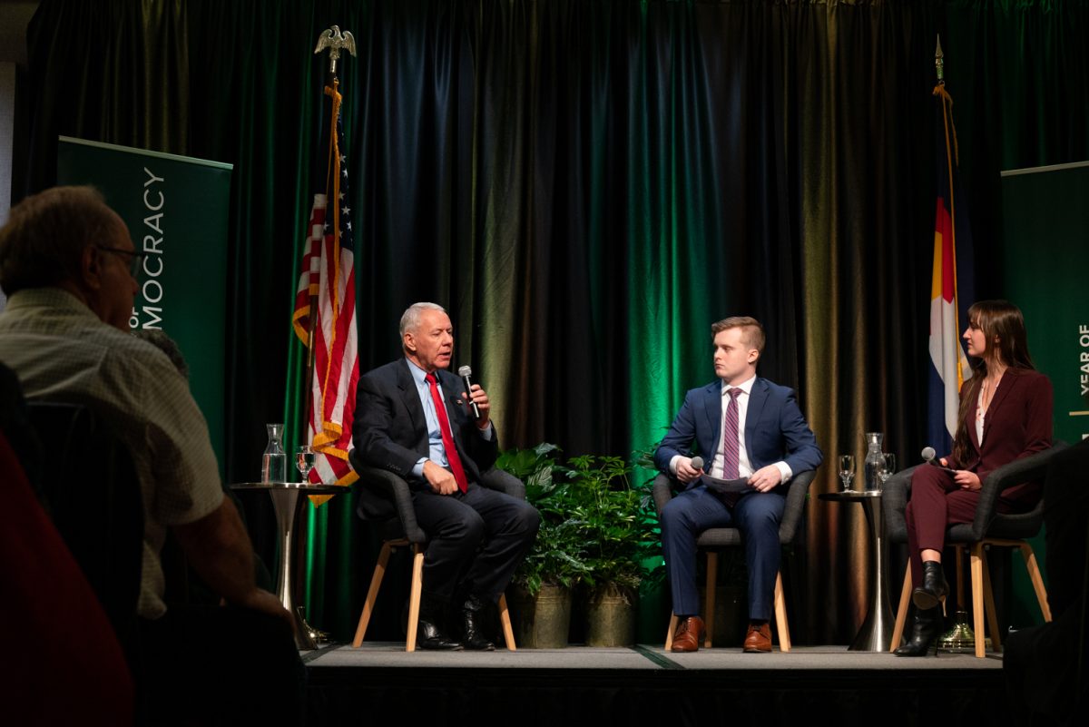 Representative Ken Buck and student moderators Jack Barrett and Amber Wright sit on stage at the Coffee with Ken Buck event in the University Ballroom.