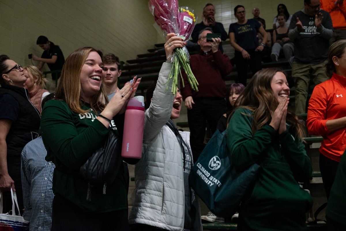 Family and friends of Colorado State University swim seniors cheer as the senior swimmers line up during senior day celebrations.