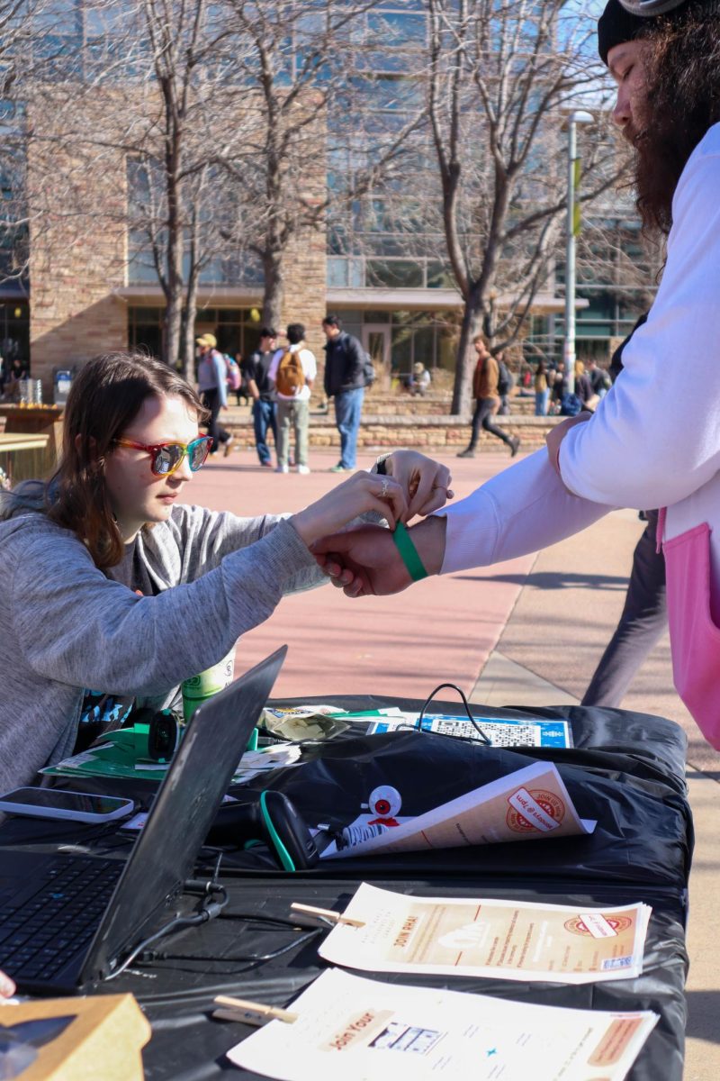 A student checks in and receives their wristband to participate in ice skating, complimentary snacks, crafts, and merchandise. Jan.31.