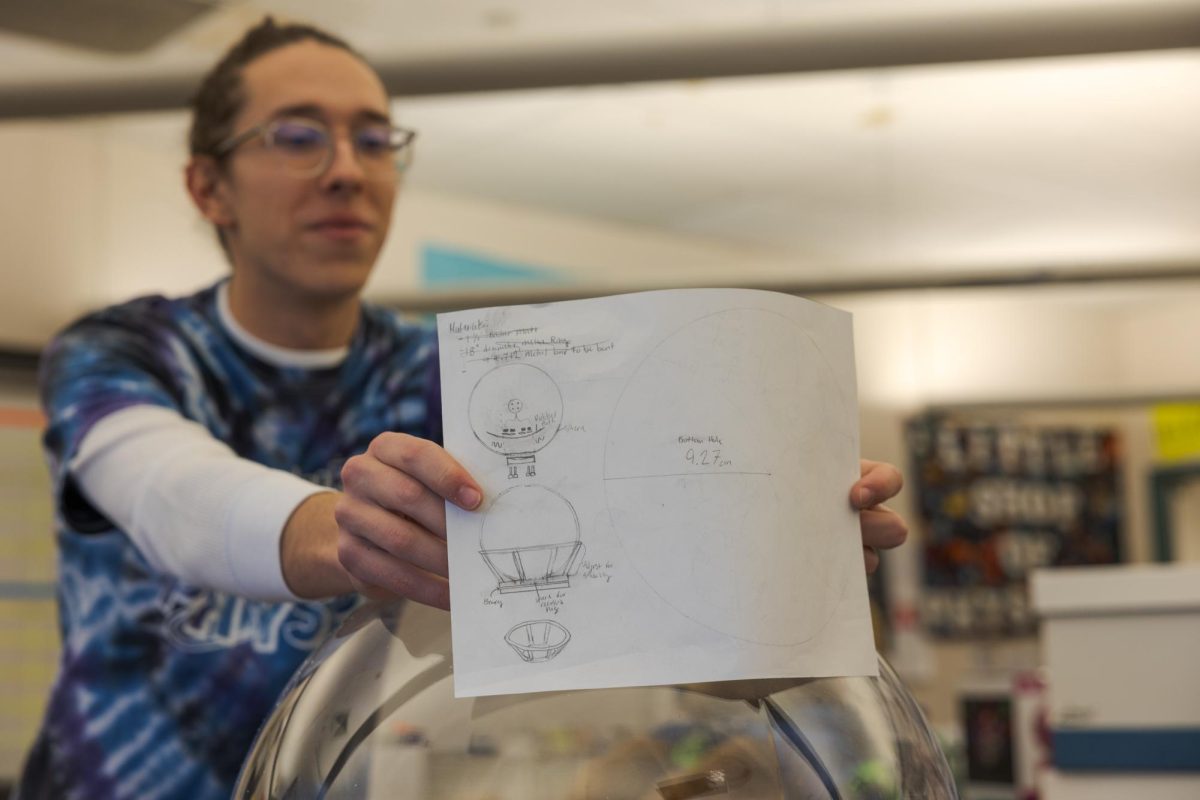 Little Shop of Physics student intern Mason McClellan shares plans for a Jupiter jar Feb. 15. The jar is filled with fluid that can simulate storms on Jupiter, according to Teacher in Residence Cherie Bornhorst.