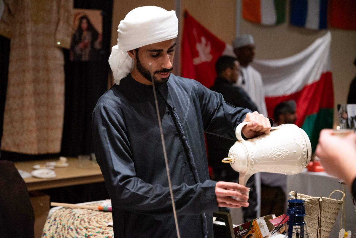 Khalifa Alghaithi pours a cup of Arabic coffee for a person visiting the United Arab Emirates booth at the World Unity Fair Feb. 17. "Arabic coffee is something important for whenever people come to our place, whenever they visit us," Alghaithi said. "We have to serve them with coffee and tea and dates. That's why we're serving everyone."