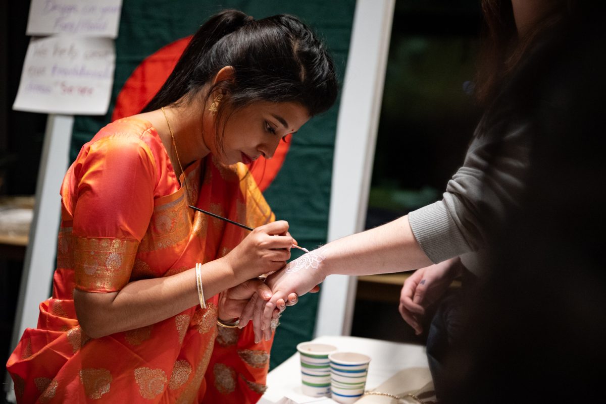A member of the Bangladesh Student Association paints an alpona design on a visitor's hand at the World Unity Fair Feb. 17. Alpona is similar to henna and is usually applied to the hand or cheek.