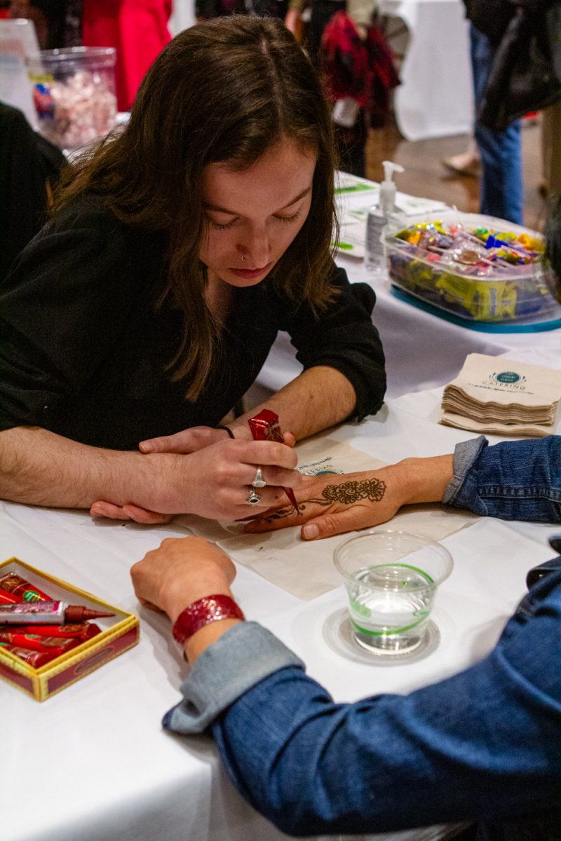 A henna artist representing the Immigrant and Refugee Center of Northern Colorado draws henna art on a visitor at the World Unity Fair located in the Lory Student Center at Colorado State University on Feb. 17. One of the event organizers Lia Arrieta said the Unity Fair booths are a mix of student clubs, student associations, and organizations from Northern Colorado. (The Collegian | Samantha Nordstrom)